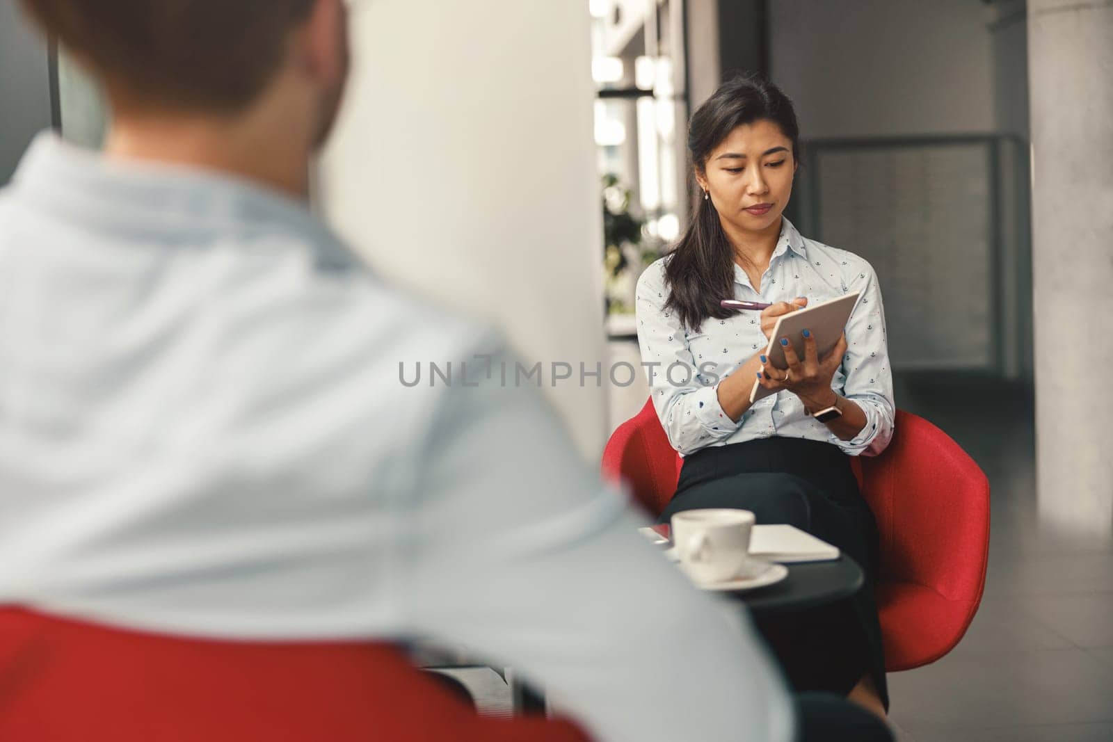 HR manager looking on digital tablet during interview with job candidate. High quality photo