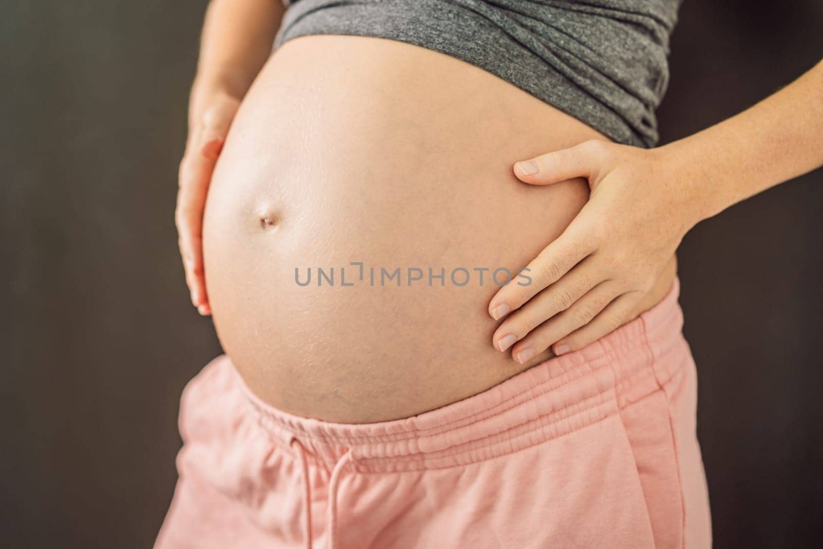 Cropped view of attractive pregnant woman touching large stomach parenthood preparation.