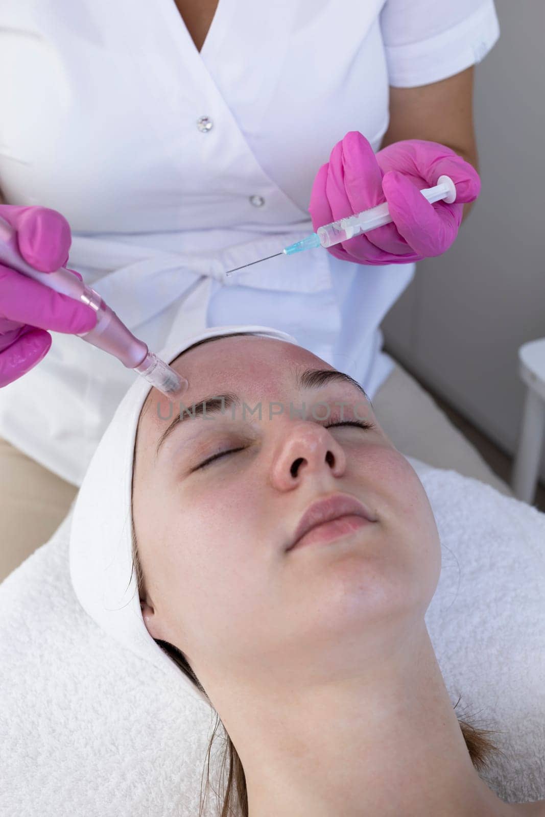 Cosmetologist Applying Peeling For Mesotherapy Injection With Dermapen On Face, Forehead Area Of Young Woman For Rejuvenation In Spa Saloon. Patient Getting Needle Mesotherapy, Skincare. Vertical