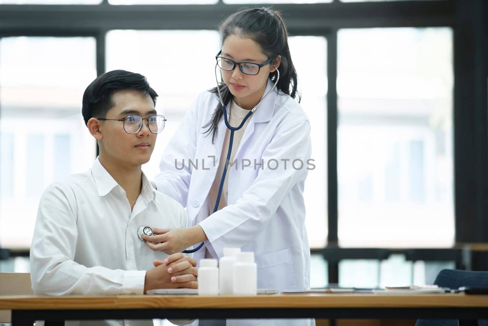 Doctor using stethoscope putting beat heart diagnose with patient in examination room at a hospital, check up body, Medical and Health Care Concept..