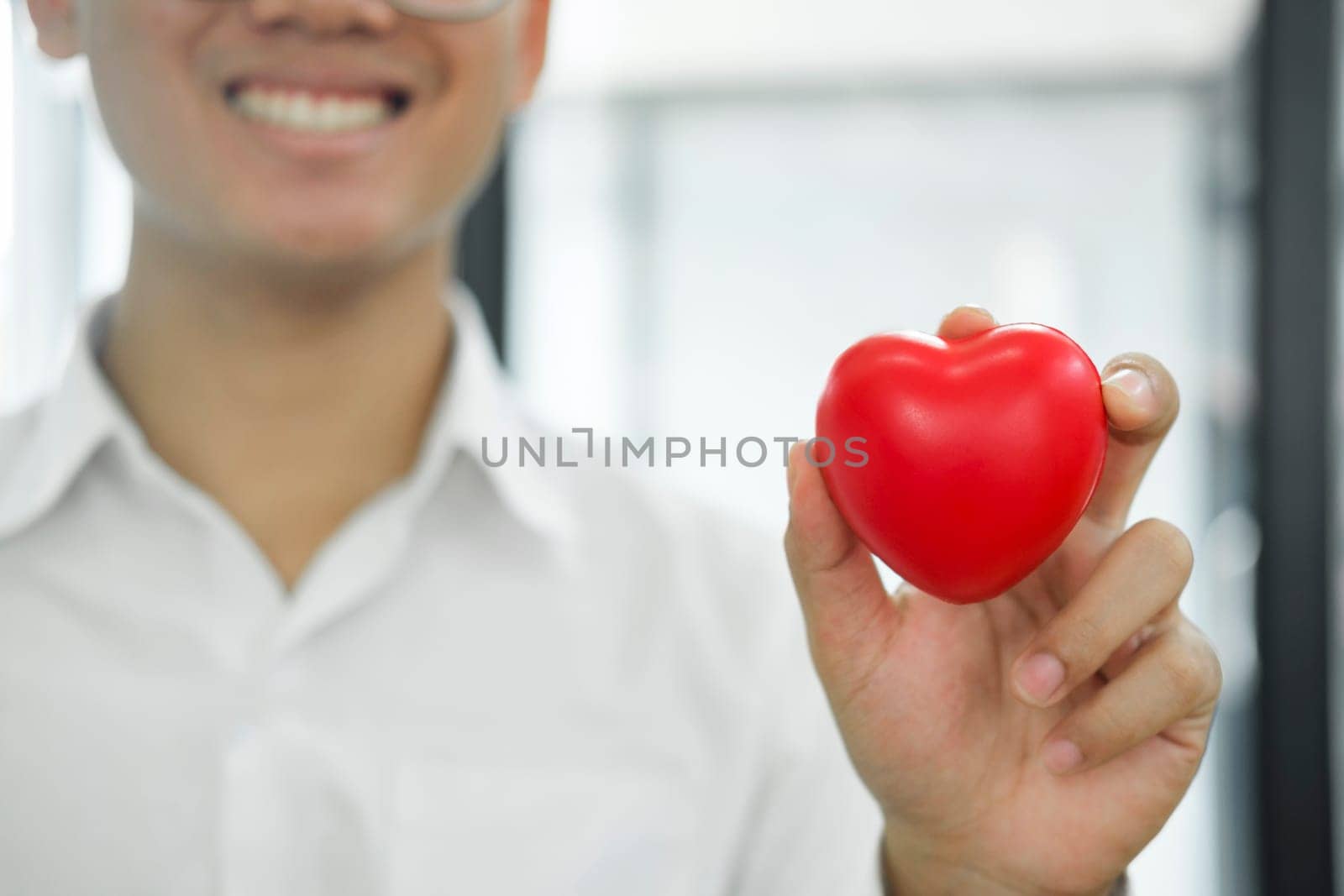 Man holding red heart shaped rubber.