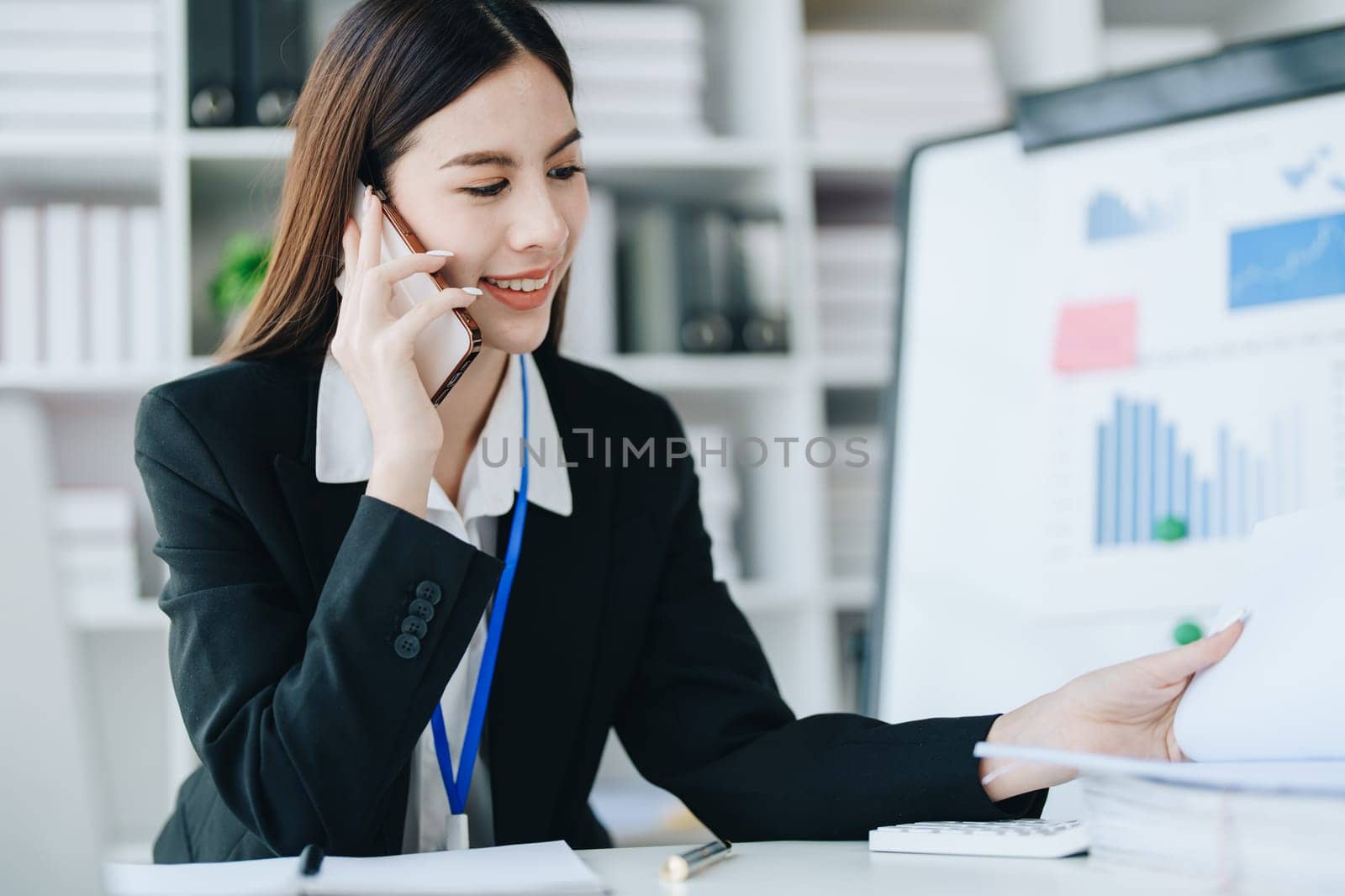 Consultant, advisor, Asian business woman working on the computer and using smartphone mobile talking work financial and marketing business planning company profits, marketing planning budget