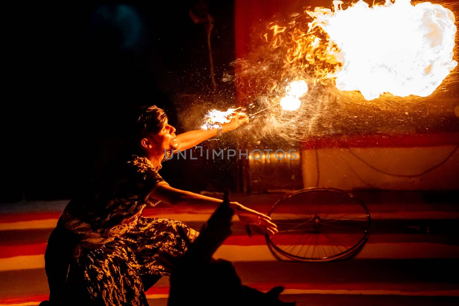 Jaisalmer, Rajasthan, India - 23rd Dec 2023: Young man in traditional rajasthan dress eating, breathing fire performance spitting showing talent and risk