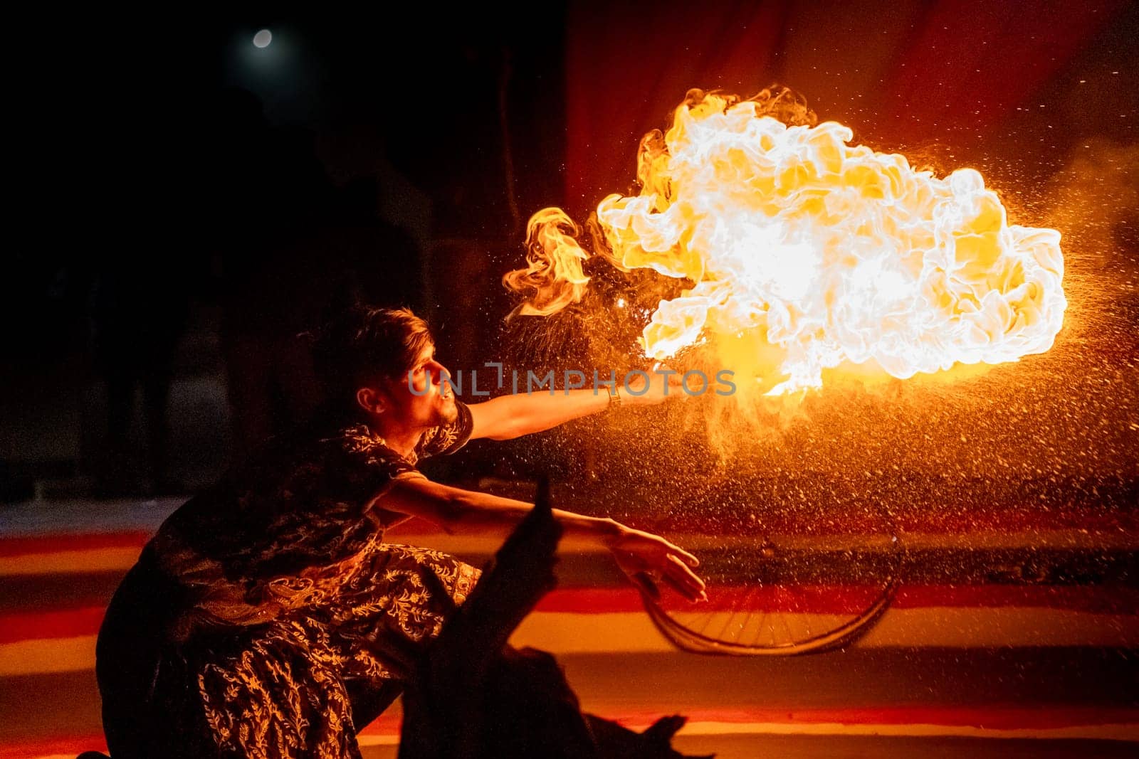 Jaisalmer, Rajasthan, India - 23rd Dec 2023: Young man in traditional rajasthan dress eating, breathing fire performance spitting showing talent and risk