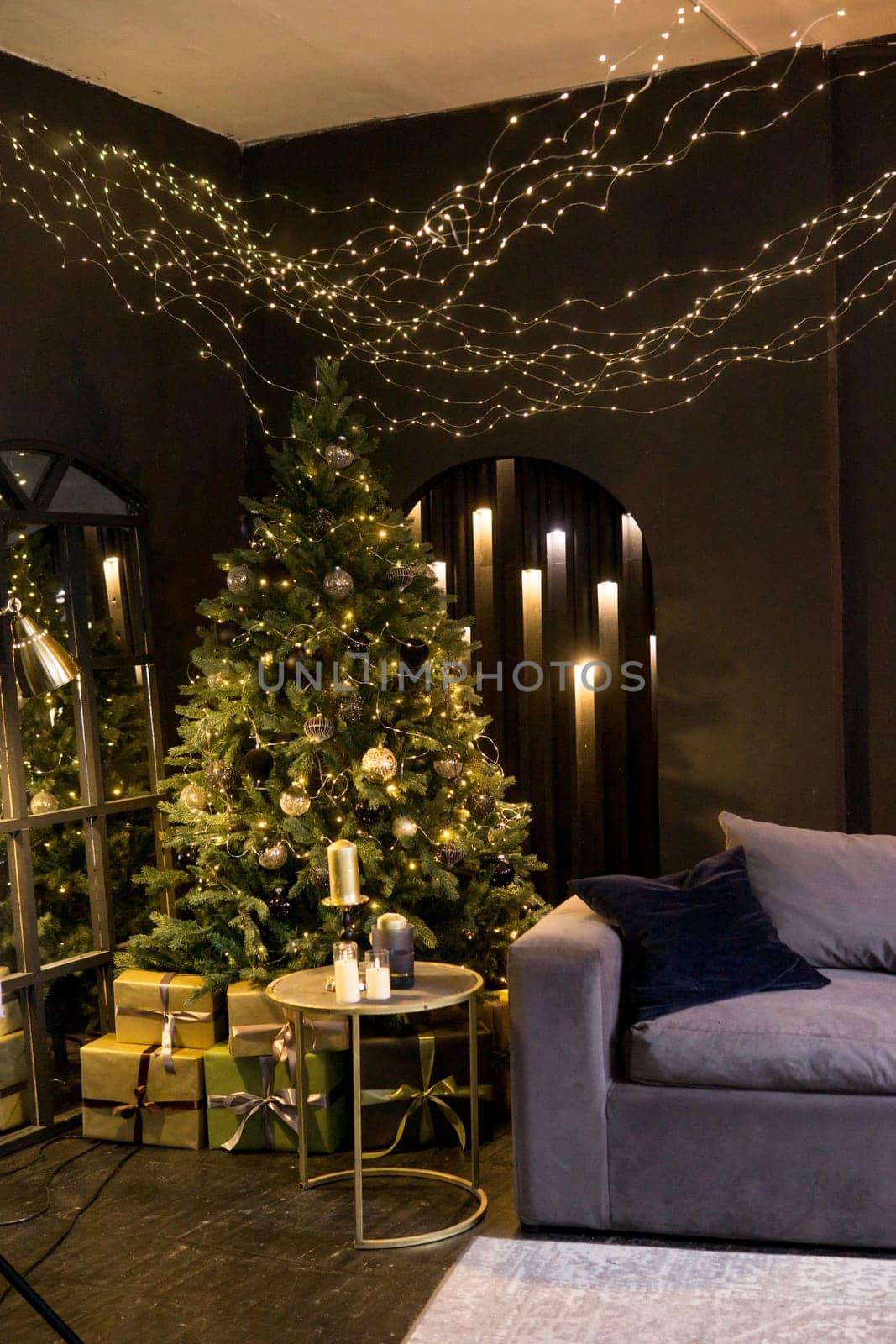 Christmas interior with a beautiful Christmas tree, sofa, light bulbs and dark background