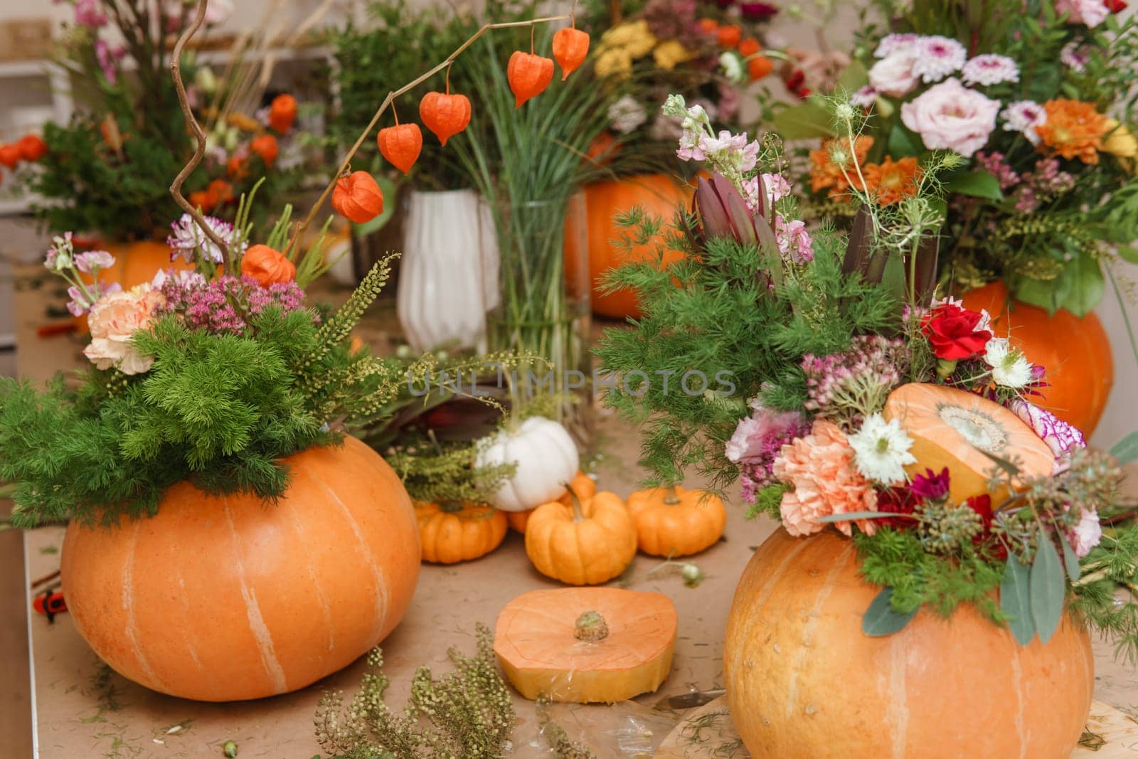 Flower arrangement in a pumpkin, autumn interior decor. Creating handmade autumn decor