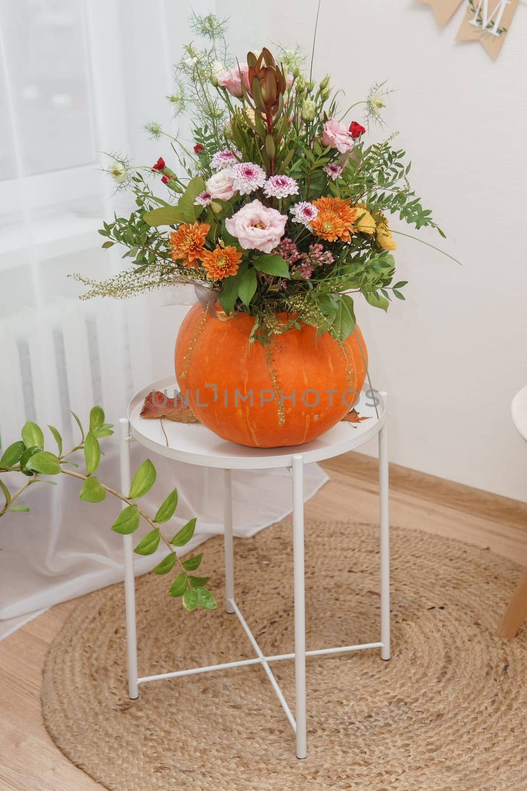 Flower arrangement in a pumpkin, autumn interior decor. Creating handmade autumn decor