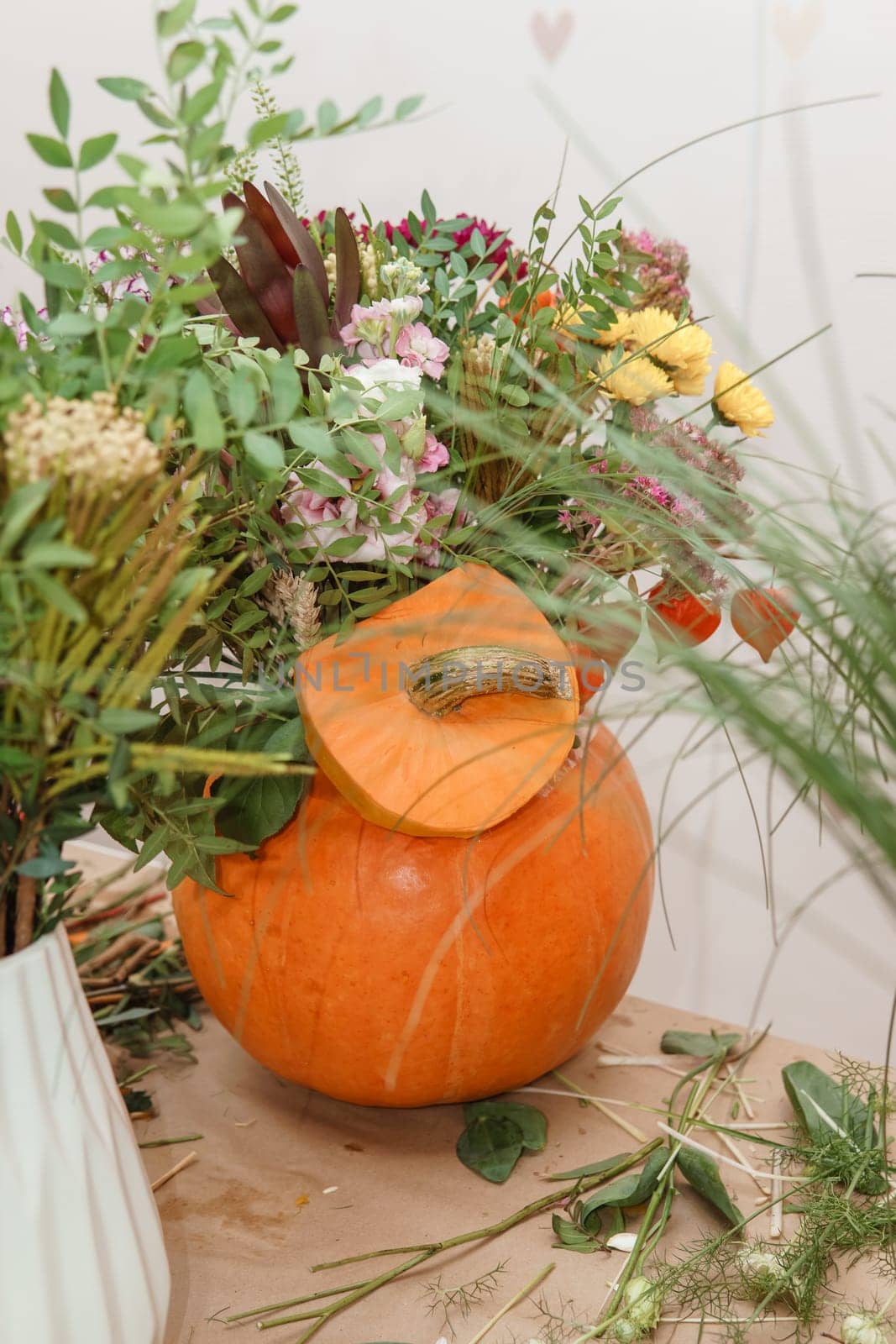 Flower arrangement in a pumpkin, autumn interior decor. Creating handmade autumn decor
