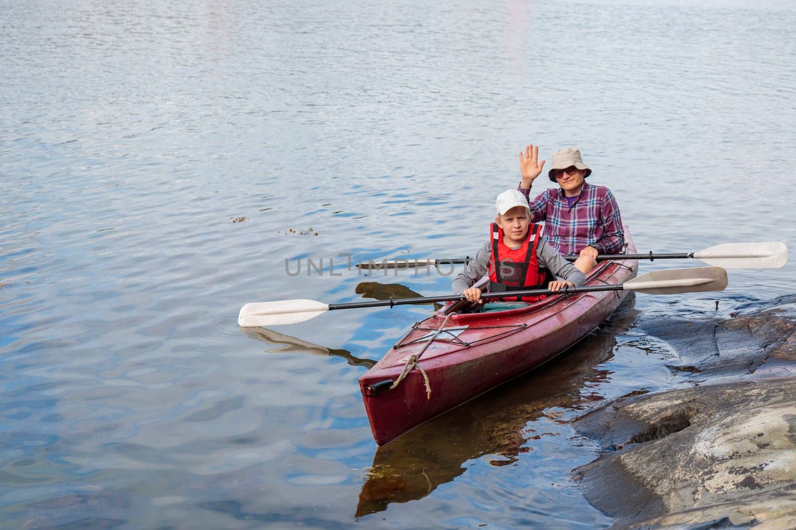 Father and son are starting to go by kayak with paddles, kayaking, canoeing, boating in the Baltic sea during family summer vacations in Finland, horizontal