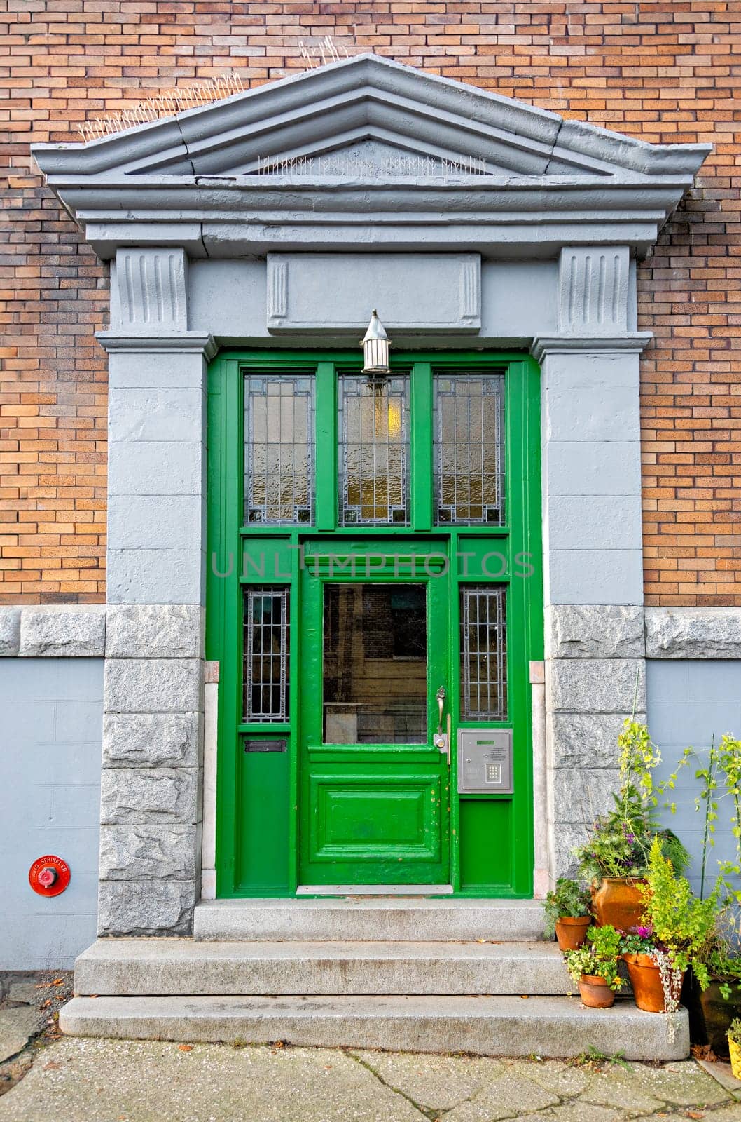 Entrance of old residential building in Vancouver decorated with flower pots.
