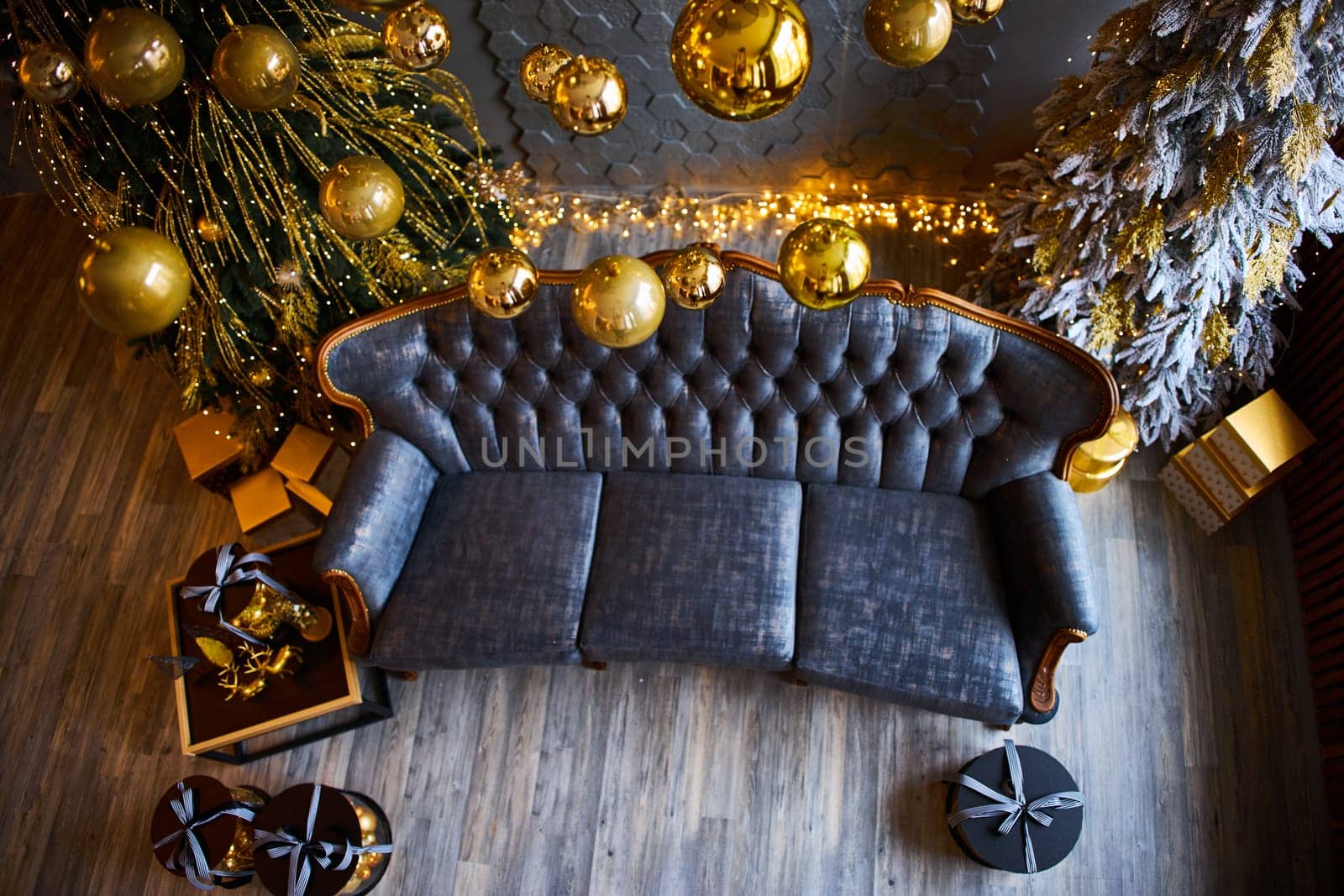 Luxurious interior of the room for Christmas and New Year. Living room in gray and gold tones with a sofa, many gifts, golden balls, ice lights, two Christmas trees. Extreme high angle shooting