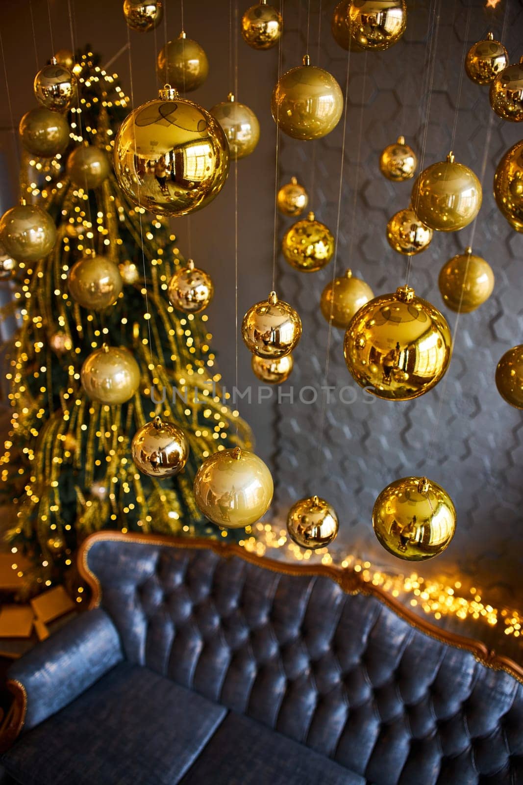 Luxurious interior of the room for Christmas and New Year. Living room in gray and gold tones with a sofa, many gifts, golden balls, ice lights, two Christmas trees. Extreme high angle shooting