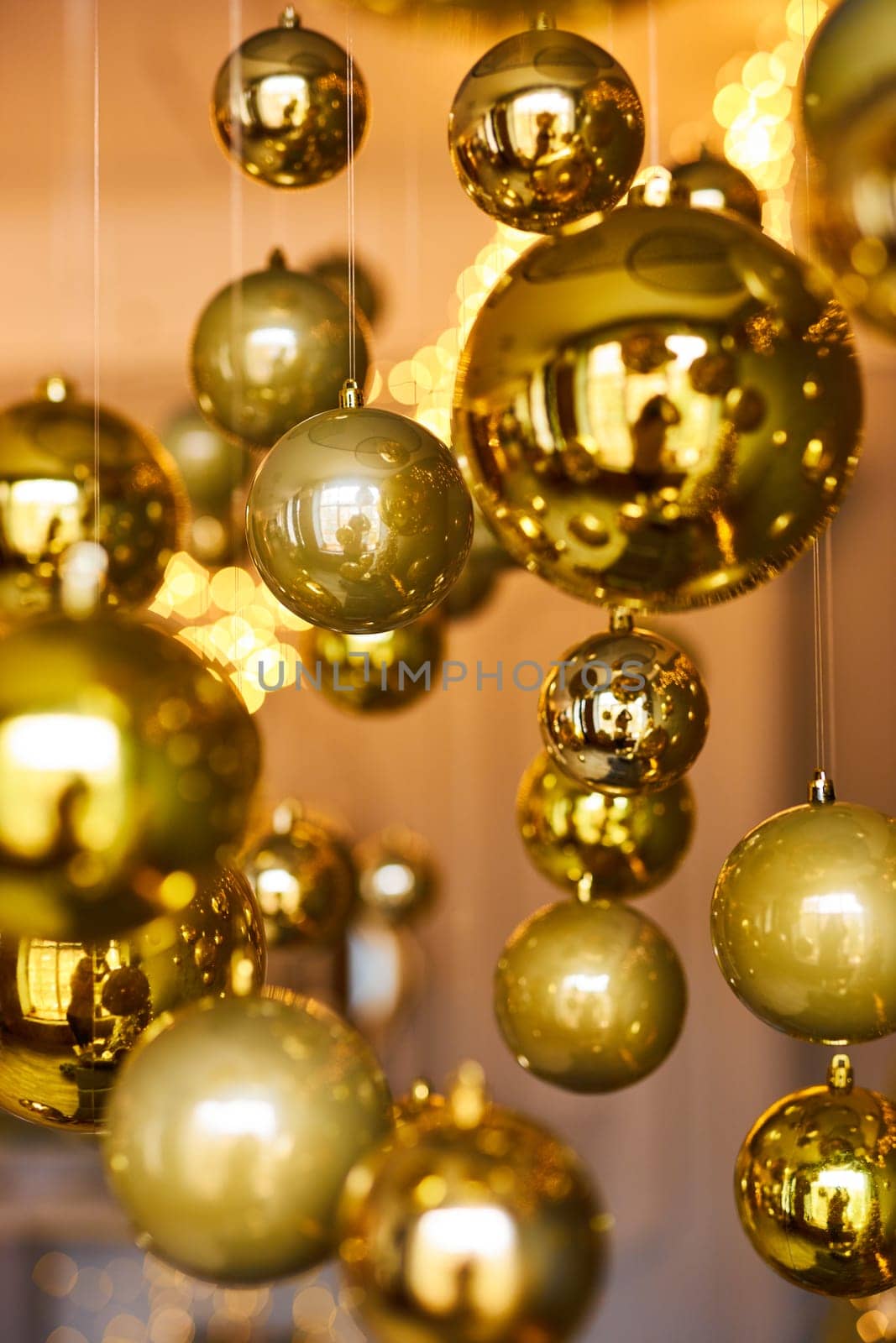Many large golden Christmas balls look hanging against the background of the Christmas interior. Festive background in golden awards, bokeh, selective focus