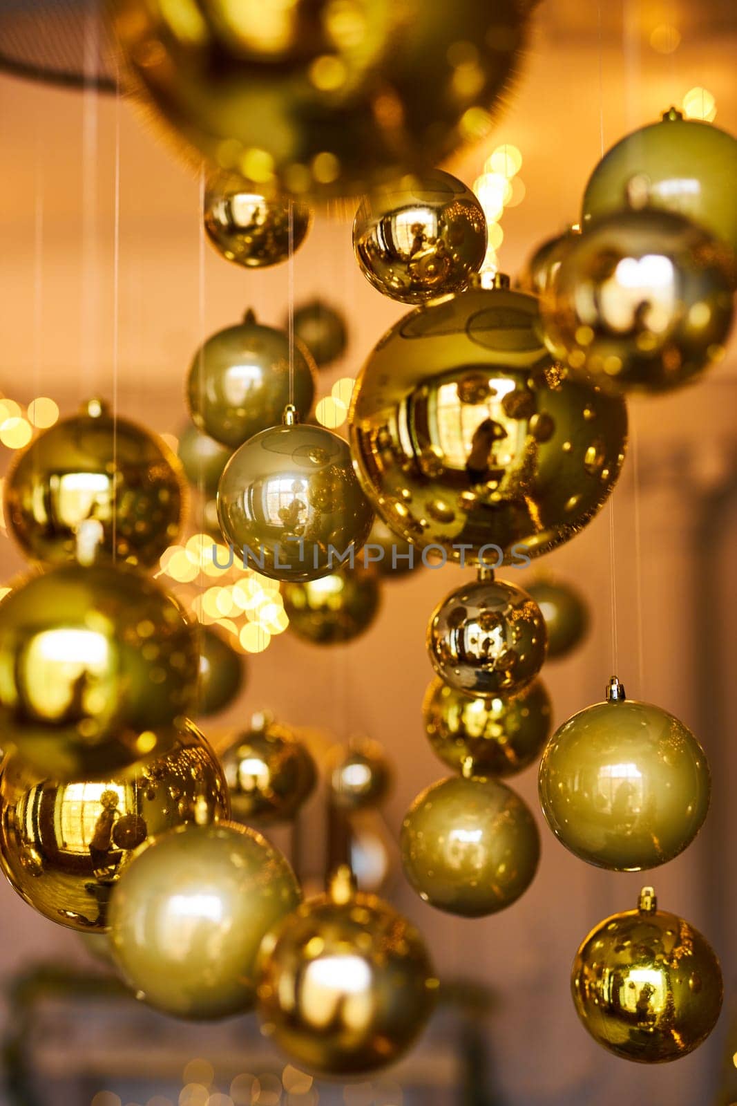 Many large golden Christmas balls look hanging against the background of the Christmas interior. Festive background in golden awards, bokeh, selective focus