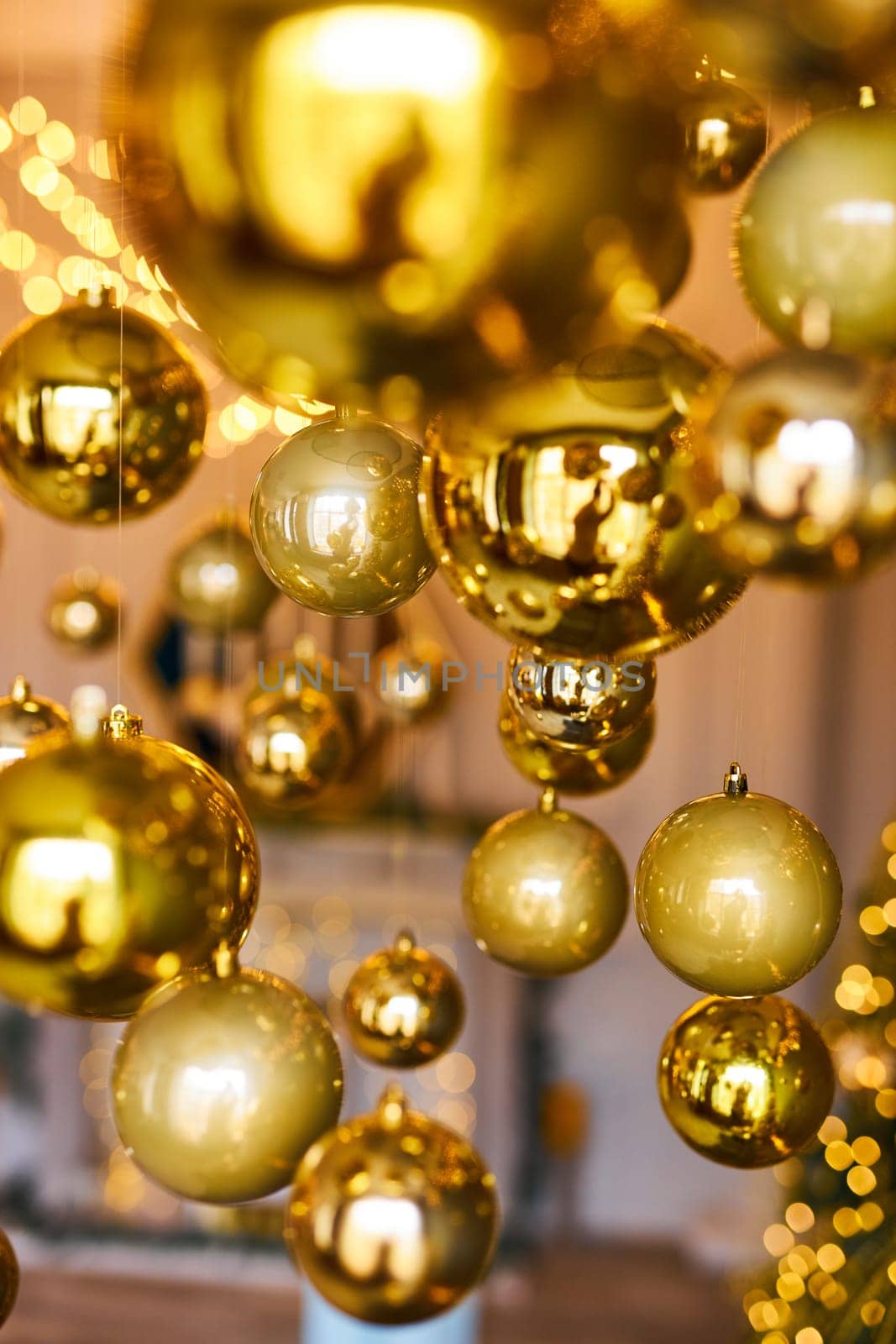 Many large golden Christmas balls look hanging against the background of the Christmas interior. Festive background in golden awards, bokeh, selective focus