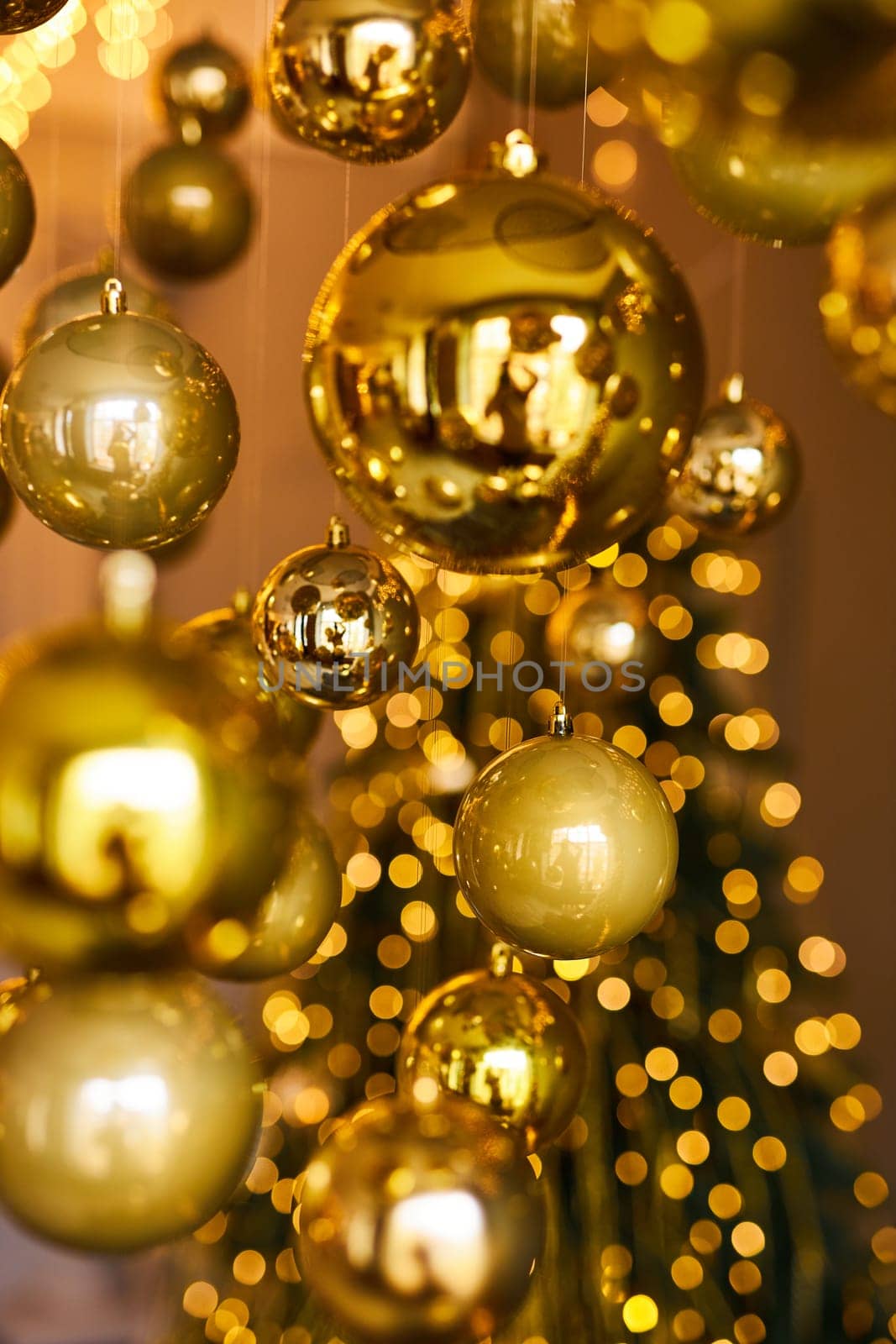Many large golden Christmas balls look hanging against the background of the Christmas interior. Festive background in golden awards, bokeh, selective focus