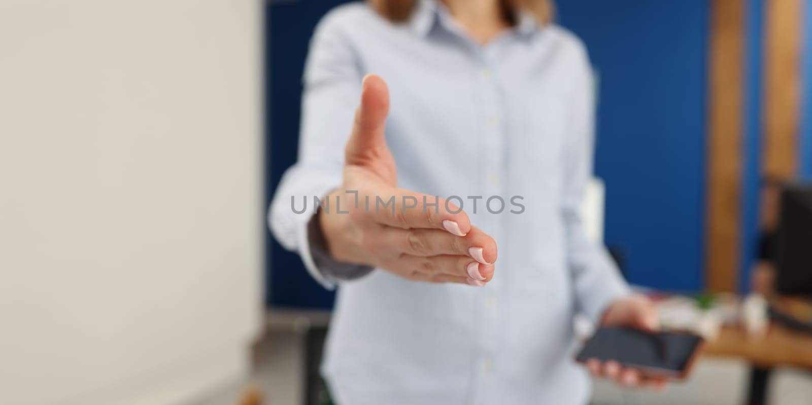 Businesswoman holds out her hand, close-up, blurry. Visit of business partners, friendly greeting of employees