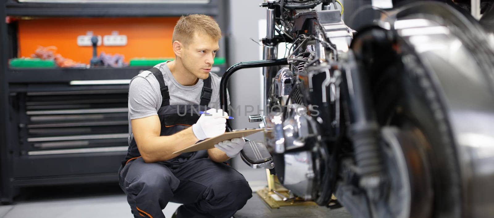 A man on a motorcycle takes notes, close-up. Checking the technical condition of the bike in the garage