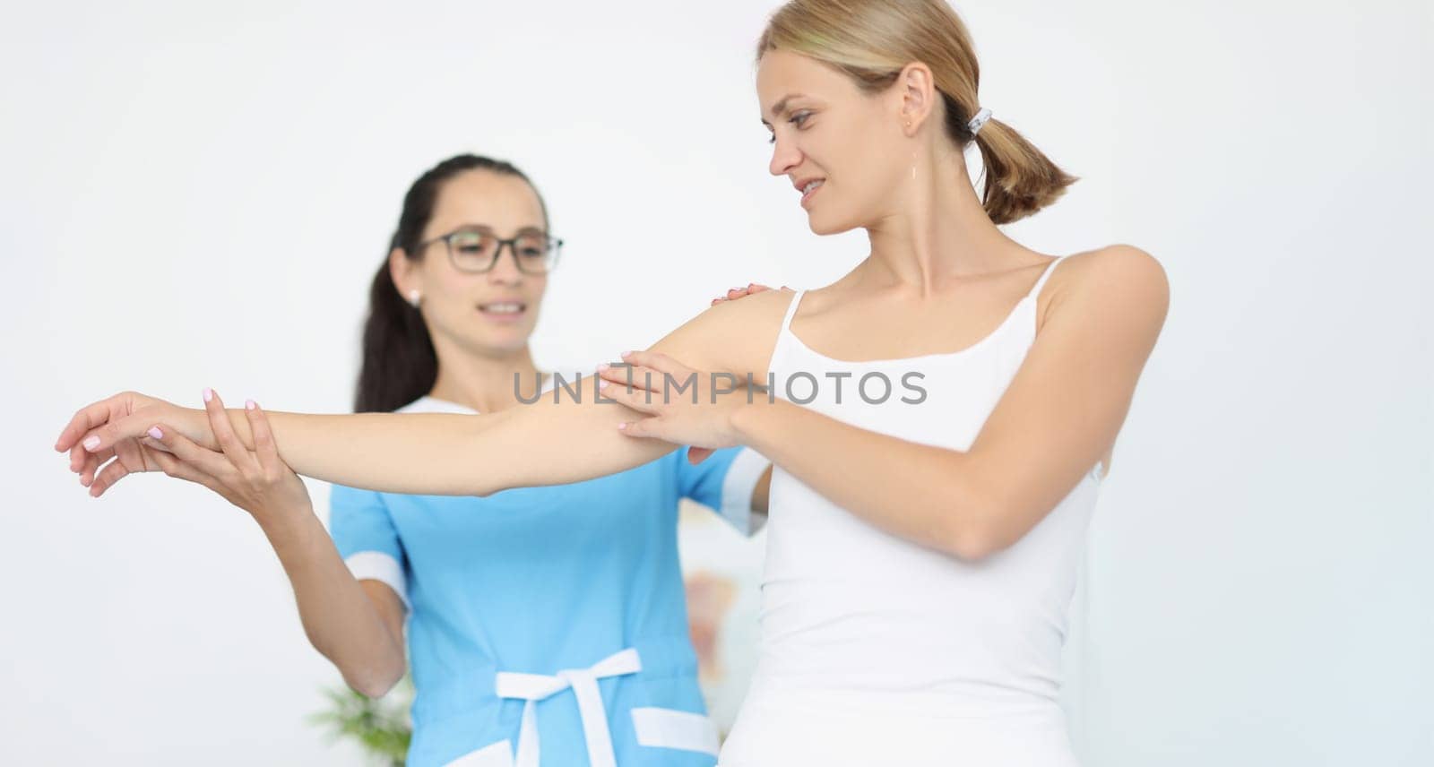 The doctor holds the hand and shoulder of a sick woman, close-up. Rehabilitation, muscle recovery, arm pain