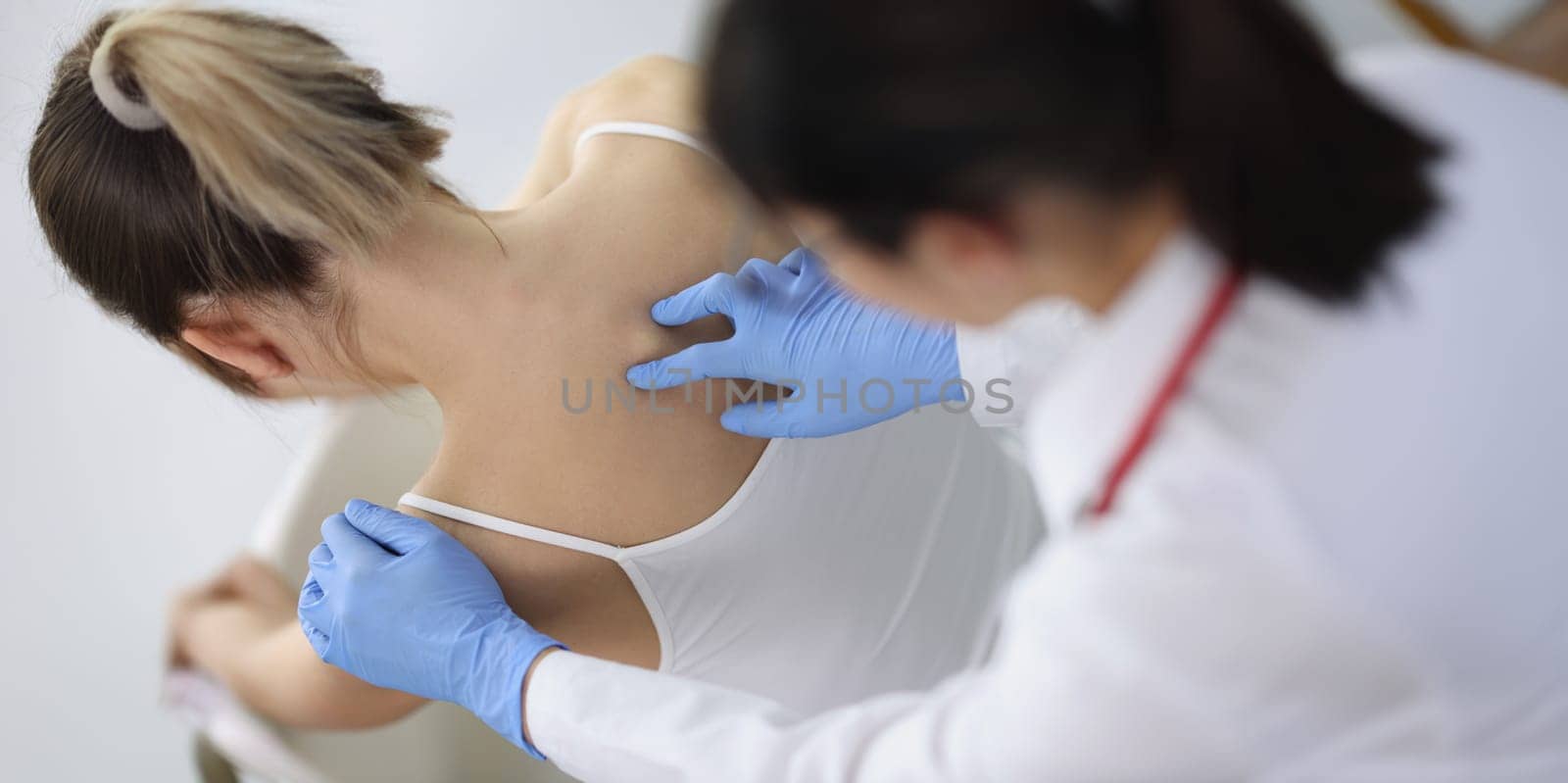 Chiropractor doctor presses on a woman's spine, close-up, top view. Osteochondrosis, physiotherapy in the clinic