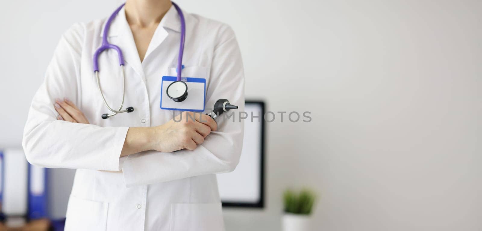 A woman otolaryngologist in a white coat holds an otoscope, close-up. Laryngologist consultation, clinic visit