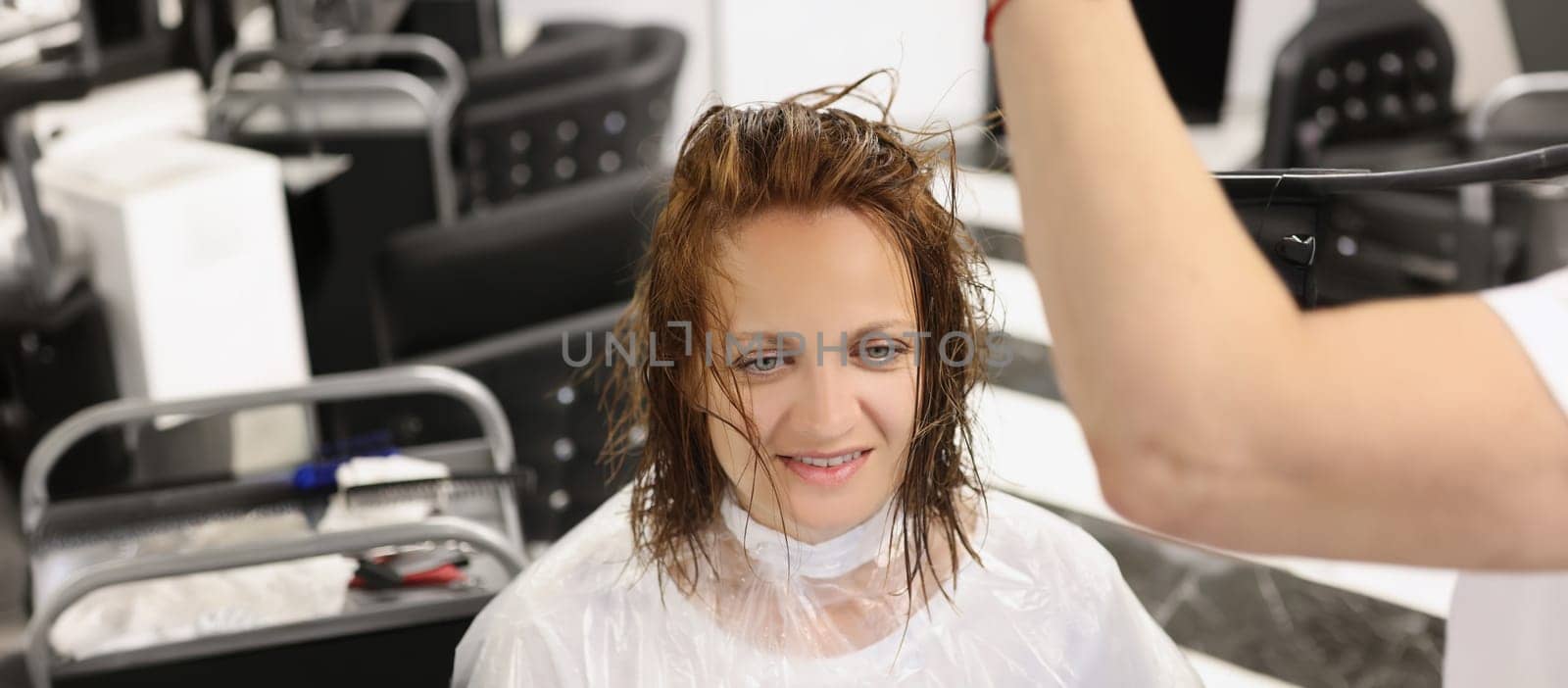 Happy woman sits in a hairdressing salon with wet hair, close-up. Painting and haircut in a beauty salon