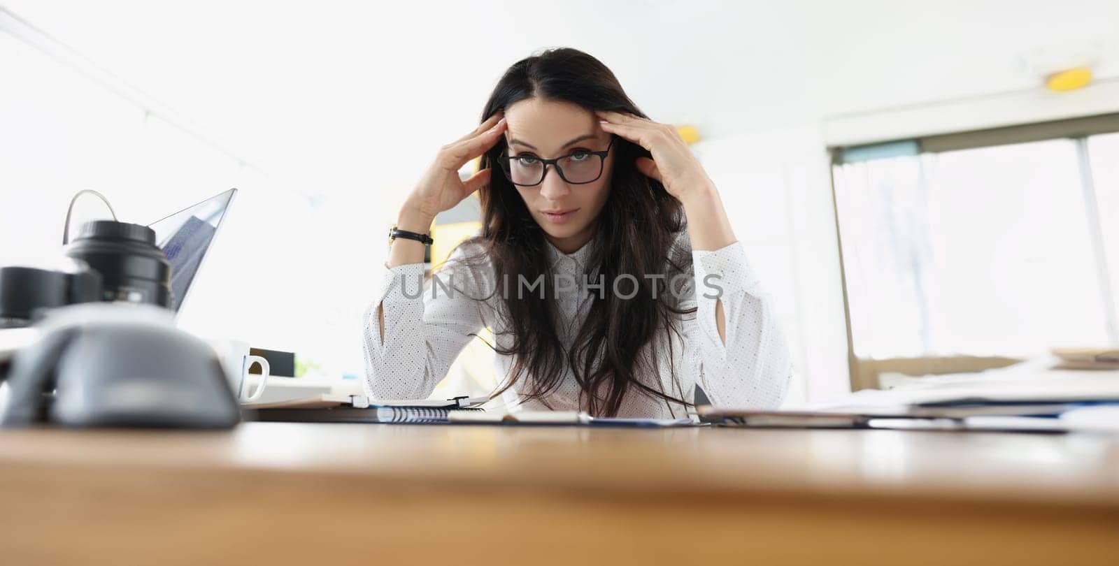 Young woman sits at the table in stress at work. Fatigue of office staff, emotional burnout, career problems