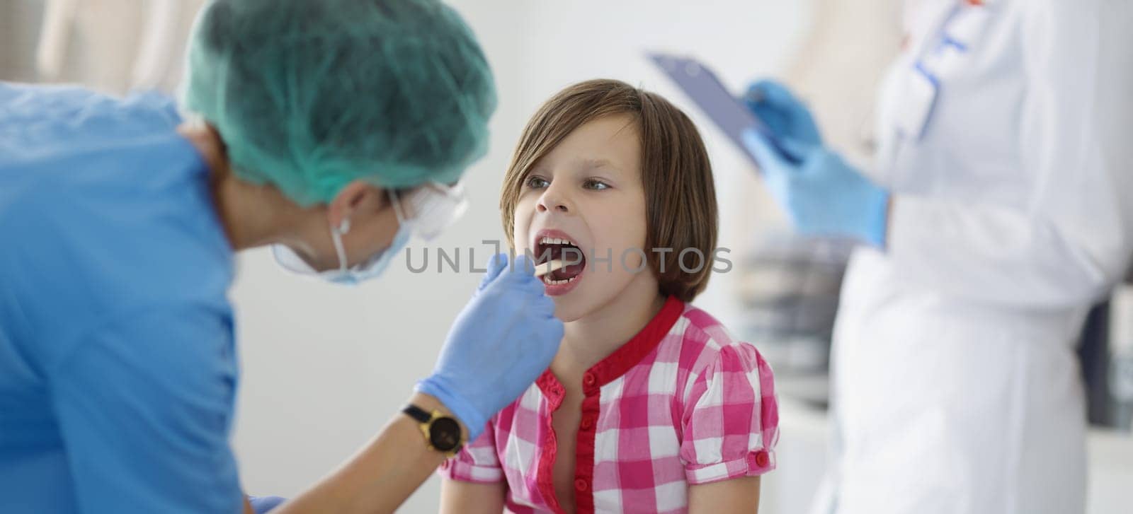 The doctor in the clinic looks at the throat of a little girl, close-up, blurry. Examination of a child by a pediatrician, diagnostics
