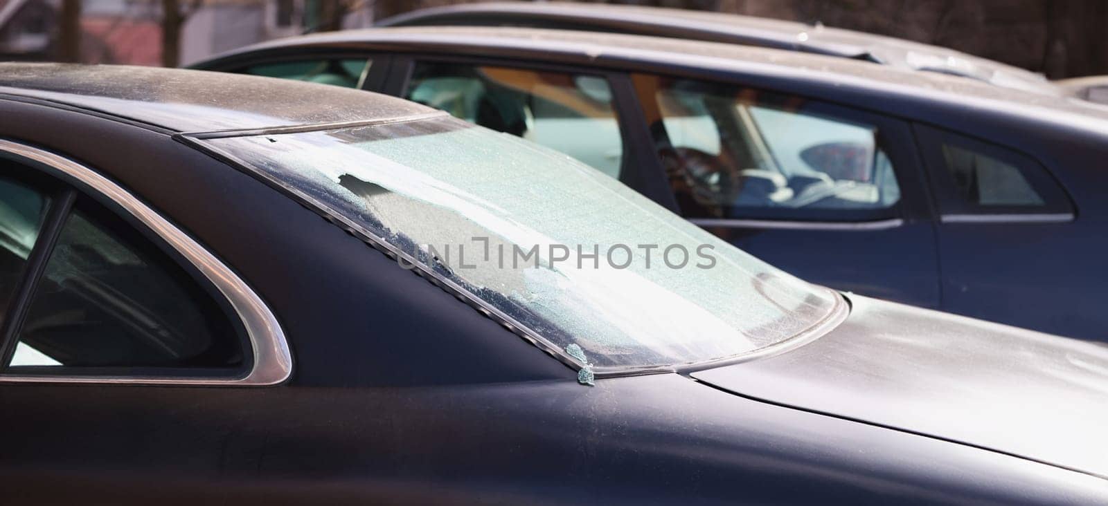 Broken rear window of a car on the street, close-up. Criminal district of the city, vandalism and theft
