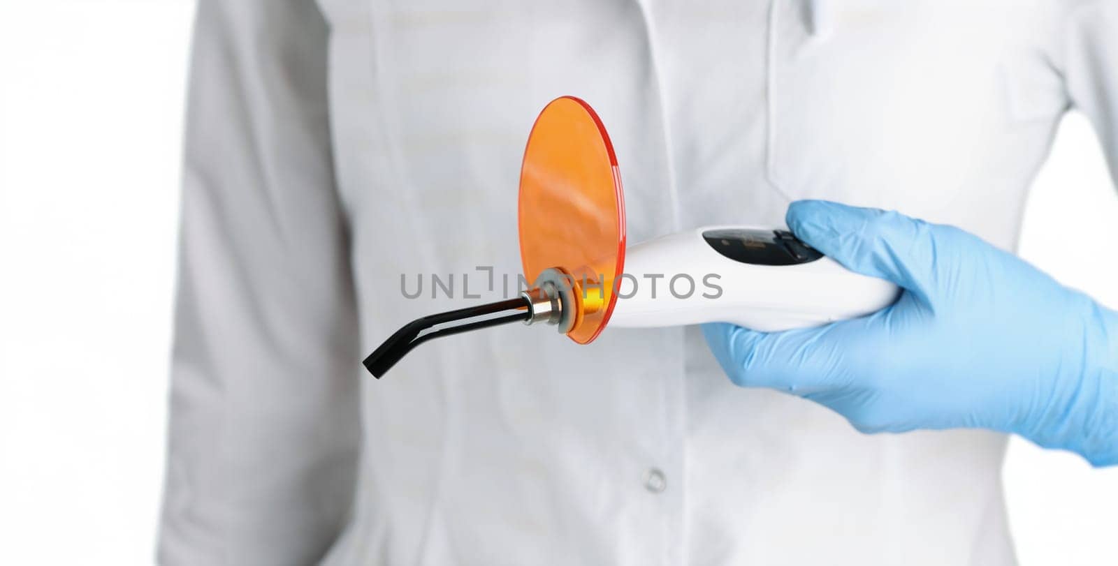 The doctor is holding dental curing light, close-up. Instruments for prosthetics fillings, solidify the teeth whitening material