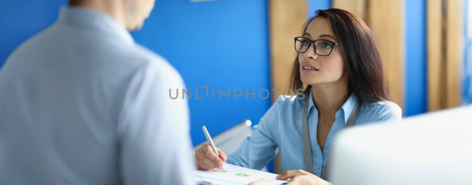 A woman in the office explains to a man a report with a diagram, close-up, blurry. Annual reporting, data analysis, correction