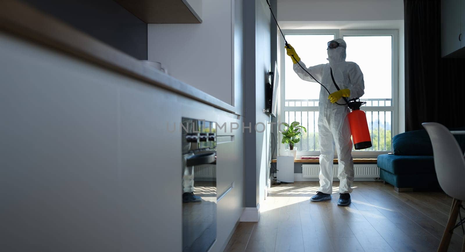 An insect control specialist in the apartment sprays the walls. Pest control. Disinfection of premises from coronavirus