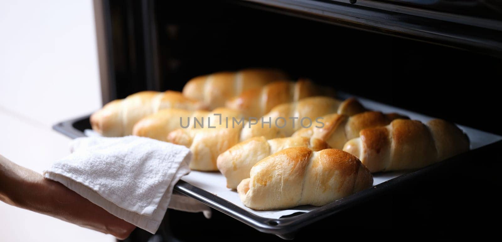 Open oven on a hot baking sheet, baked goods, close-up. Homemade croissants, puff pastry sausage, bun recipe