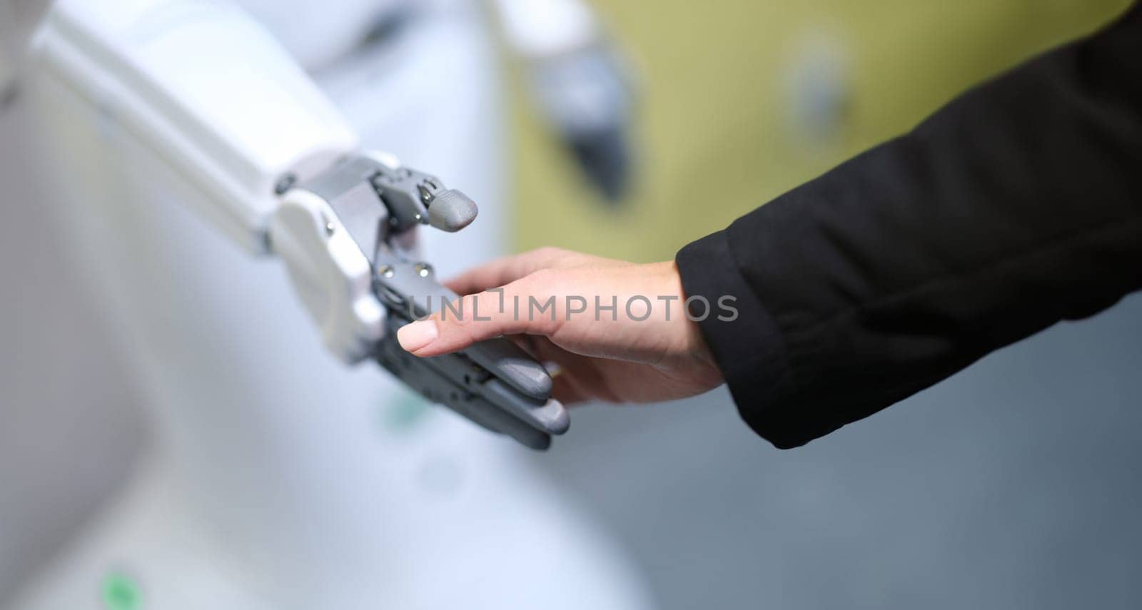 Human and robot handshake, hands close-up, blurry. Human mechanical assistant. Tactile sensitivity, artificial intelligence