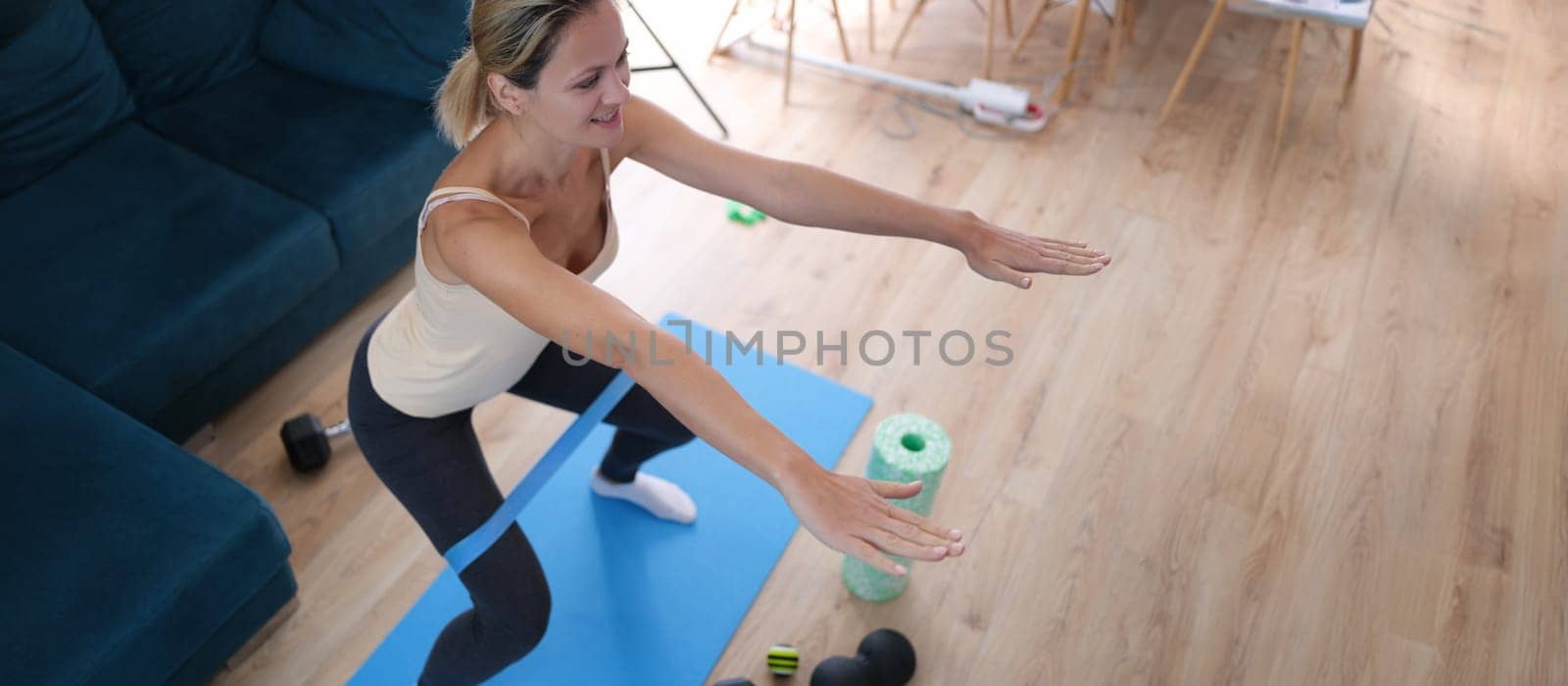 Woman with elastic band on her legs doing squats, close-up. Stretching and aerobics at home during a pandemic