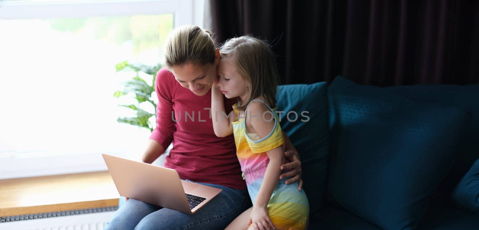 A little girl speaks to her mother with a laptop, close-up. Sharing time at home with a child, parental attention