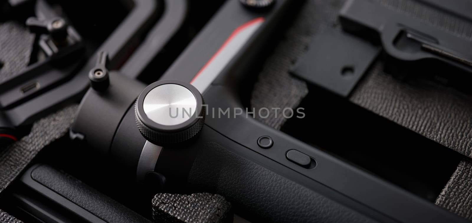 Folded tripod for a video camera on a black background, close-up. Body muscle massage percussion gun