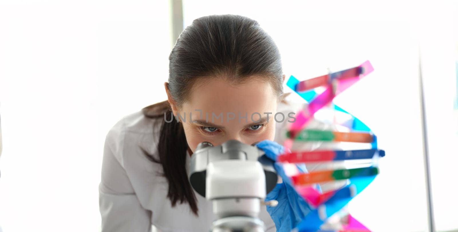 A woman biologist looks through a microscope close-up. DNA sample. Genetics research. Pharmaceutical laboratory