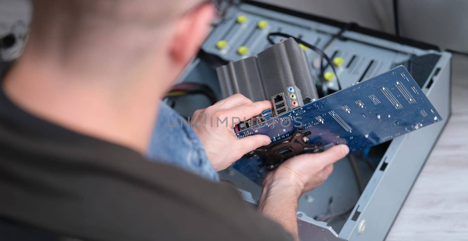 The man took out the motherboard from the computer, close-up. Processor repair and pc heatsink replacement