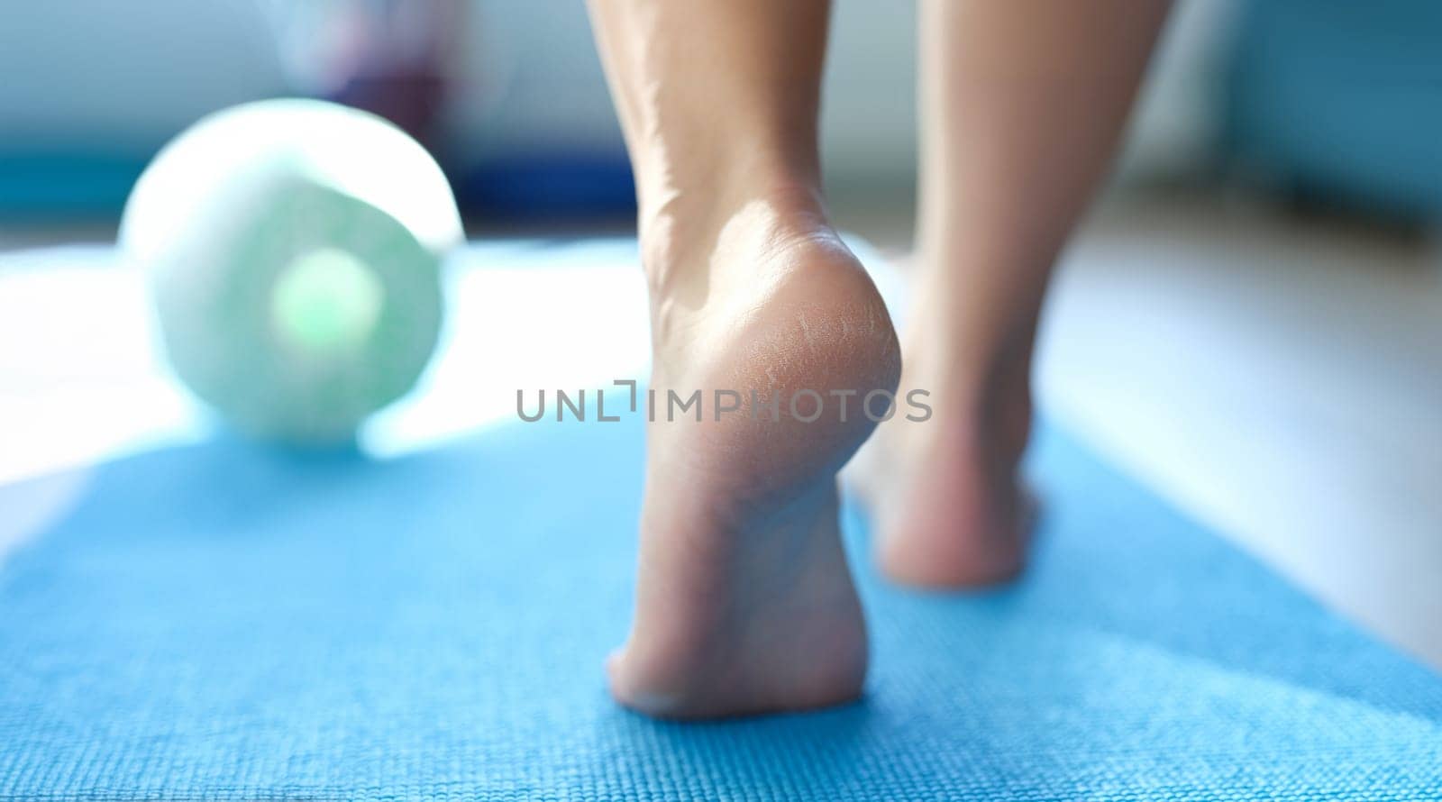 Barefoot dry feet make a step on a sports mat, rear view, close-up. Rough skin of the feet, cracked heels