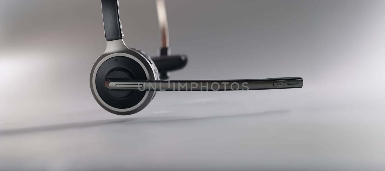 Wireless headset with a microphone on a gray background, close-up. Call center equipment, one ear. Working from home