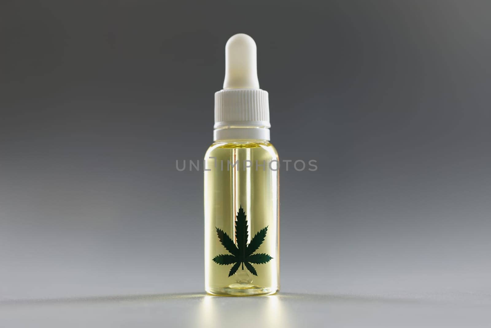 Hemp oil with a dispenser on a gray background, close-up. Pharmaceutical medical drug with cannabis, dropper