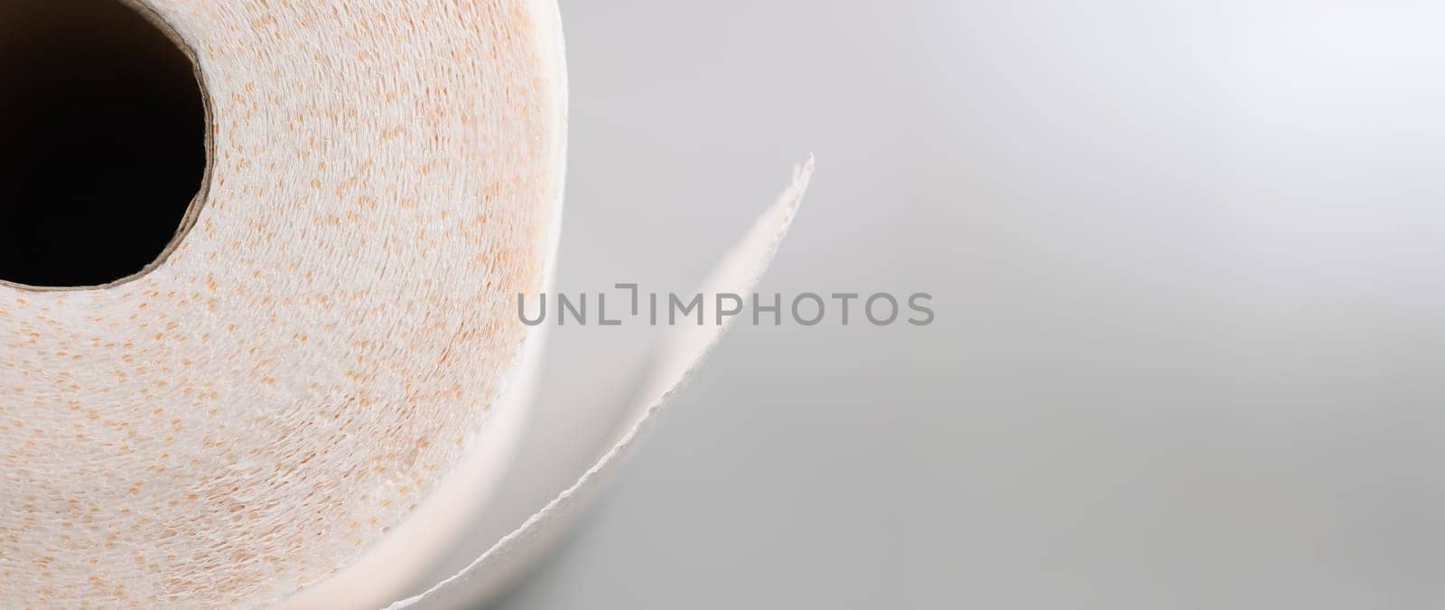 Close-up of a roll of soft toilet paper on a gray background. Texture of loose white kitchen napkin, recyclable