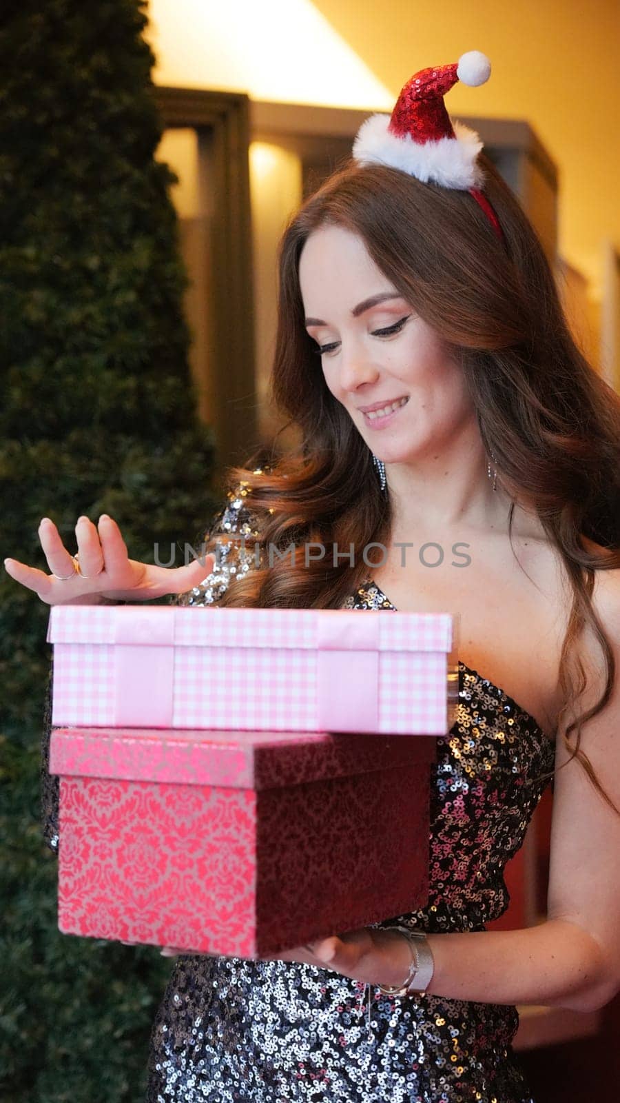 Girl holding Christmas present near New Year tree. Happiness emotions. High quality photo