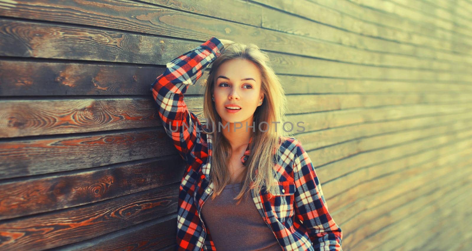 Portrait of beautiful caucasian blonde young woman in casual checkered shirt in the city