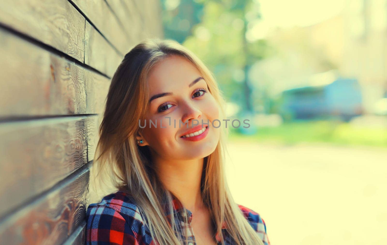 Portrait of beautiful caucasian blonde smiling young woman looking at camera in the city