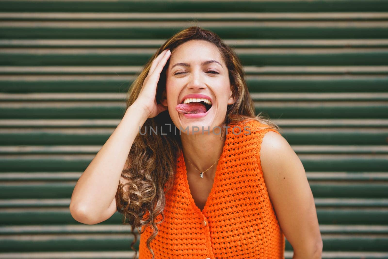 Urban portrait of a latin beauty woman flirting sticking the tongue out smiling at camera