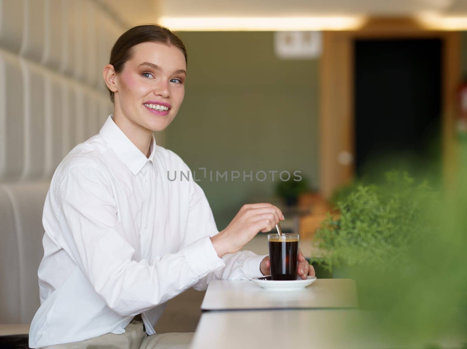Side view of an elegant caucasian adult beauty businesswoman drinking coffee in a modern cafeteria