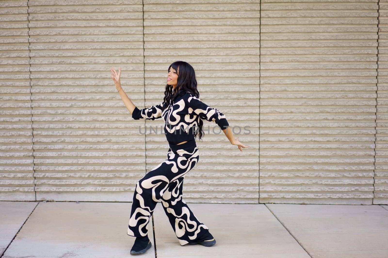 Full length photo of an hispanic female expressive dancer performing modern movements dancing in the city