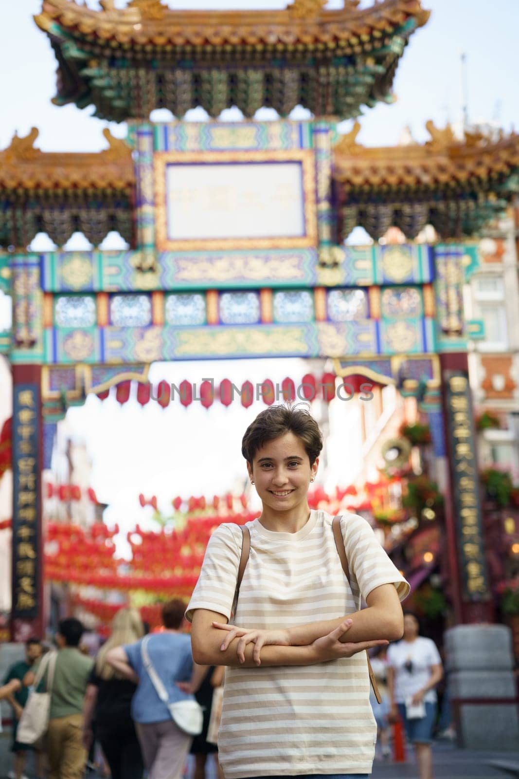 Teenage girl posing with her arms crossed at one of the entrance gates of Chinatown in London, UK.